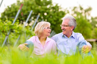 Senior Couple or pensioners, man and woman, sitting in vineyard on summer